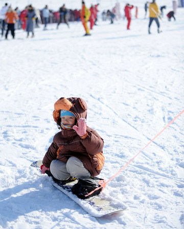 A boy plays with a snowboard at a park in Lotus Hill of Changchun, capital of northeast China's Jilin Province November 23, 2008. [Xinhua]