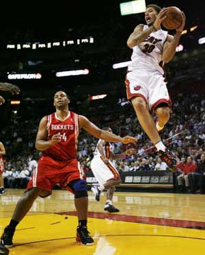 Miami Heat's Michael Beasley (R) grabs a rebound from Houston Rockets Chuck Hayes during first quarter NBA basketball action in Miami Nov. 24, 2008. [Xinhua/Reuters]