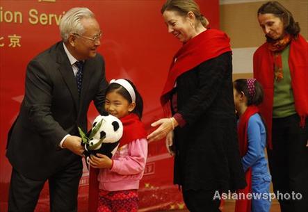 Li Xueju(left), Minister of Civil Affairs, gives a souvenir to a China-born girl who is adopted by an American family. 