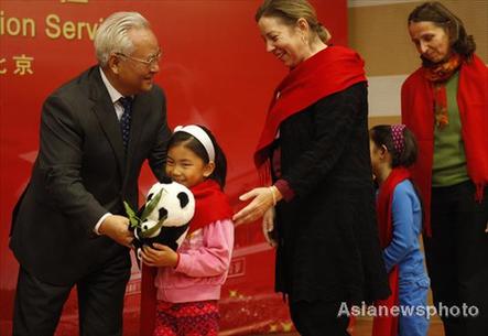 Li Xueju(left), Minister of Civil Affairs, gives a souvenir to a China-born girl who is adopted by an American family. [Asianewsphoto]