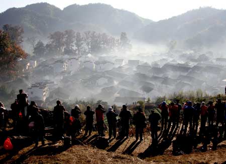 Photography lovers take pictures of the Shicheng Village hidden in the mist during the early morning in Wuyuan City, east China's Jiangxi Province, Nov. 25, 2008. [Xinhua]