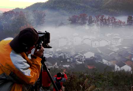 Photography lovers take pictures of the Shicheng Village hidden in the mist during the early morning in Wuyuan City, east China's Jiangxi Province, Nov. 25, 2008. [Xinhua]