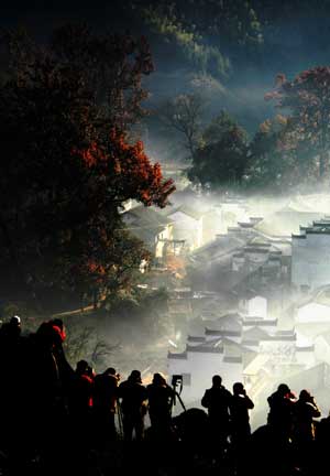 Photography lovers take pictures of the Shicheng Village hidden in the mist during the early morning in Wuyuan City, east China's Jiangxi Province, Nov. 25, 2008. [Xinhua]