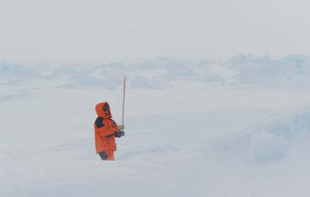 A member of ice detection team measures the depth of the snow on ice with a stick while searching for routes for the blocked China