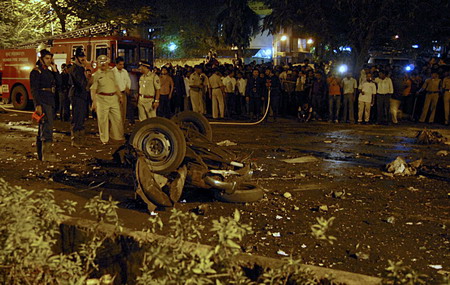 Onlookers stand at the site of a bomb blast in Mumbai November 26, 2008. At least 80 people were killed in a series of attacks apparently aimed at tourists in India's financial capital Mumbai on Wednesday night, with television channels saying Westerners were being held hostage at two five-star hotels. 