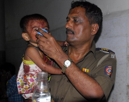 A policeman gives water to an injured child at a hospital in Mumbai November 26, 2008. At least 10 people were killed and 26 wounded in a series of shootings around India's financial capital Mumbai on Wednesday night, with two five-star hotels among the targets in what police called a terror attack. Maharahstra state police chief A.N. Roy said attackers had fired automatic weapons indiscriminately, and used grenades, adding that they were still holed up in some buildings.