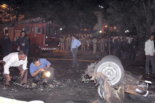 Onlookers stand at the site of a bomb blast in Mumbai November 26, 2008. At least 80 people were killed in a series of attacks apparently aimed at tourists in India&apos;s financial capital Mumbai on Wednesday night, with television channels saying Westerners were being held hostage at two five-star hotels. At least 250 people have been wounded, police said.