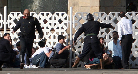 People run for cover as gunshots are fired from inside the Taj Mahal hotel in Mumbai November 27, 2008. Maharashtra state police chief A.N. Roy said on Thursday that the hostage situation had ended at the Taj Hotel in Mumbai, but that there were still apparently hostages in the Trident/Oberoi. 