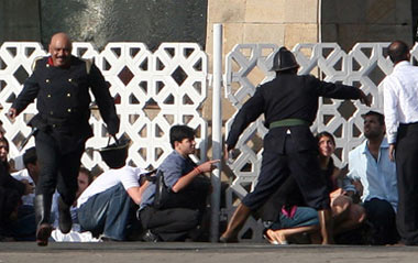 People run for cover as gunshots are fired from inside the Taj Mahal hotel in Mumbai November 27, 2008. Maharashtra state police chief A.N. Roy said on Thursday that the hostage situation had ended at the Taj Hotel in Mumbai, but that there were still apparently hostages in the Trident/Oberoi.