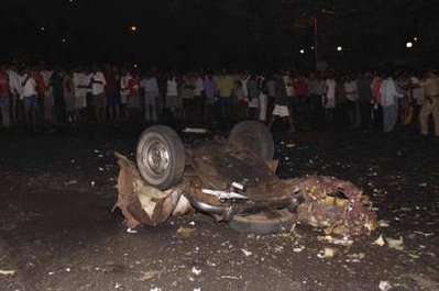 Onlookers stand at the site of a bomb blast in Mumbai November 26, 2008. A witness told Indian television that gunmen in India's financial hub of Mumbai looked for British and U.S. passport holders.