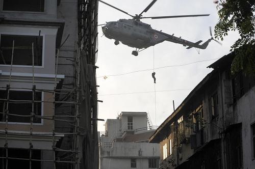 An Indian National Security Guard (NSG) commando abseils from a helicopter onto the rooftop of Nariman House at Colaba Market in Mumbai on November 28, 2008. At least 17 commandos have abseiled from a helicopter onto the roof of a Jewish centre in Mumbai taken by Islamic militants and entered the building as gunfire erupted, an AFP witness said. 