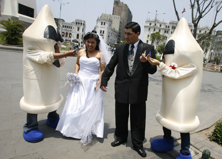 A recently married couple receives condoms from people dressed as condoms during an AIDS and HIV prevention campaign at the square in downtown Lima Nov. 28, 2008. [Xinhua/Reuters]