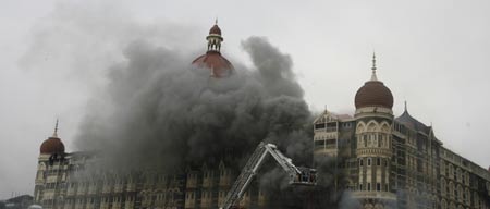 Firefighters douse a blaze from Taj Mahal Hotel after a gun battle in Mumbai November 29, 2008. Operations by Indian commandos to dislodge Islamist militants at Mumbai's Taj Mahal hotel ended on Saturday, Indian television channels quoted officials as saying. The hotel came under heavy gunfire and flames leaped out of the building shortly before the announcement. [Agencies] 