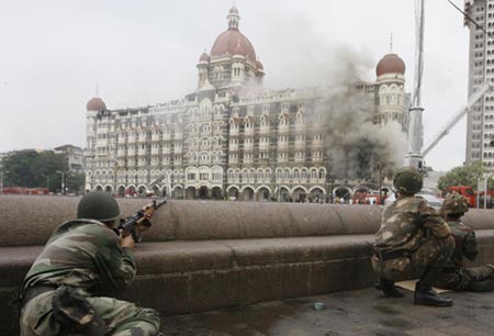 Indian army soldiers take position during a gun battle at the Taj Mahal hotel (seen in the background) in Mumbai November 29, 2008. Operations by Indian commandos to dislodge Islamist militants at Mumbai's Taj Mahal hotel ended on Saturday, Indian television channels quoted officials as saying. The hotel came under heavy gunfire and flames leaped out of the building shortly before the announcement. [Agencies]