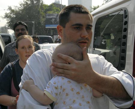  A hotel guest carries a baby while being evacuated from the besieged Trident-Oberoi Hotel in Mumbai November 28, 2008. At the hotel, commandos killed two militants and freed 143 guests earlier in the day. [Agencies]