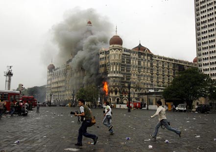  Photographers run past burning Taj Mahal Hotel during a gun battle in Mumbai November 29, 2008. [Agencies]