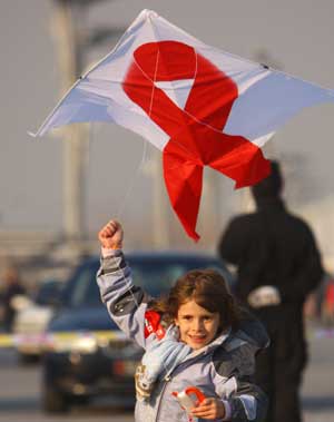 A child flies a kite with a red ribbon during a World AIDS Day event at the Olympic Green in Beijing, capital of China, Nov. 30, 2008. UNAIDS and China Red Cross on Sunday jointly organized an event 'One Goal One Dream - of a world without Stigma', in commemoration of the World AIDS Day 2008 which falls on Dec. 1. [Xinhua Photo]