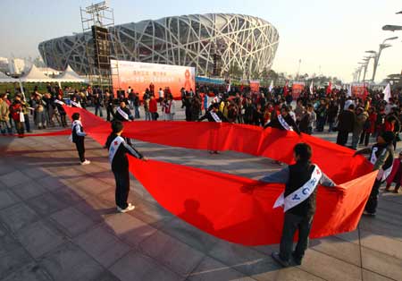 Volunteers form a red ribbon during a World AIDS Day event at the Olympic Green next to the Bird Nest in Beijing, capital of China Nov. 30, 2008.[Xinhua Photo]