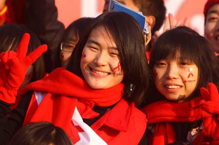 Volunteers wear red ribbons on their faces during a World AIDS Day event at the Olympic Green in Beijing, capital of China Nov. 30, 2008.[Xinhua Photo]