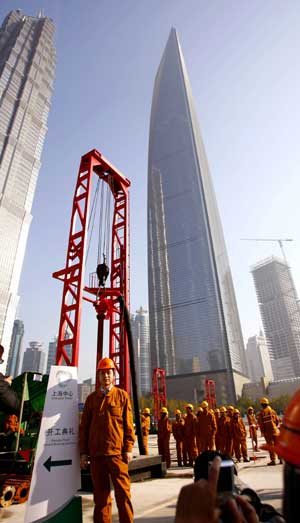 A worker poses for a photo at the building site of Shanghai Center with Jin Mao Tower and Shanghai World Financial Center in the backdrop in Shanghai, east China, on Nov. 29, 2008. [Xinhua]
