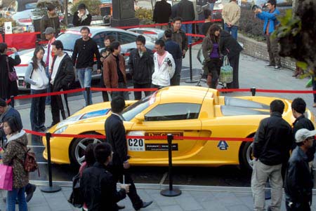 People look at Porsche roadsters in Wuhan, capital of central China's Hubei Province, Nov. 30, 2008. Forty-five Porsche roadsters taking part in a charity travel organized by Hong Kong Porsche Club were exhibited in Wuhan on Sunday.[Xinhua]