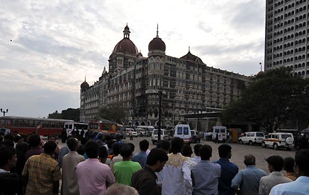Indian people look at Taj Mahal Hotel where terrorist attack took place in Mumbai, India, Nov. 30, 2008. After the final siege at the Taj Mahal hotel, lives of people live in Mumbai began to return to normal. But the main areas, which were attacked by the terrorists, are still blocked by the police.(Xinhua/Liu Sui Wai)