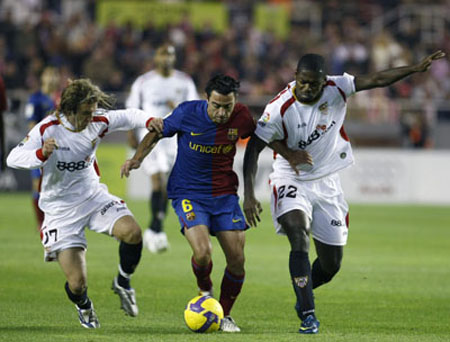 Barcelona's Xavi Hernandez (C) fights for the ball between Sevilla's Diego Capel (L) and Ndri Romaric during their Spanish First Division soccer match at Ramon Sanchez Pizjuan stadium in Seville Nov. 29, 2008. 