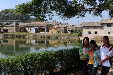 Students walk past an artifical lake dug in ancient China's Ming Dynasty (1368-1644) at Dalu Village, Lingshan County, southwest China's Guangxi Zhuang Autonomous Region, Nov. 14, 2008. [Xinhua]