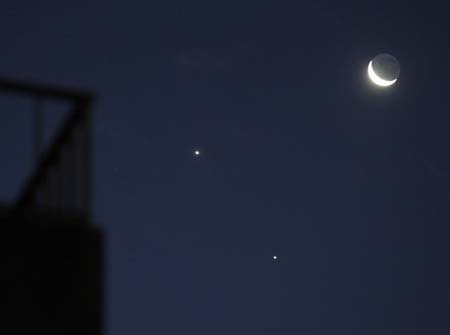  A crescent moon and the planets Jupiter (bottom) and Venus are seen in the sky over Buenos Aires December 1, 2008. Astronomers and skygazers across the world are keeping watch on Monday night for a rare astronomical phenomenon as two of the brightest naked-eye planets, Venus and Jupiter, join a thin crescent moon to create a brief 'unhappy face' in the sky. [Xu Suhui/Xinhua]