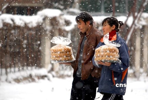 Two Uygur locals walk through the snow with food they bought for the upcoming Corban Festival on December 23rd in Urumchi, capital of northwestern China's Xinjiang Uygur Autonomous Region, on Tuesday, December 3rd, 2008. Cold air swept through Xinjiang bringing heavy snow to the northern part of the region. [Photo: cnsphoto]