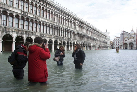Tourists take photos of each other in the flooded Saint Mark's square in Venice December 1, 2008. Large parts of Venice were flooded on Monday as heavy rains and strong winds lashed the lagoon city, with sea levels at their highest level in 22 years. [China Daily via Agencies] 
