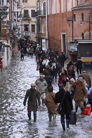 Pedestrians wade through flood waters in Venice December 1, 2008. Large parts of Venice were flooded on Monday as heavy rains and strong winds lashed the lagoon city, with sea levels at their highest level in 22 years. [China Daily via Agencies] 