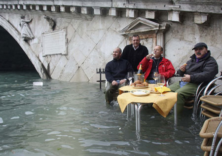 Gondoliers eat breakfast while sitting in flood waters in Venice December 1, 2008. Large parts of Venice were flooded on Monday as heavy rains and strong winds lashed the lagoon city, with sea levels at their highest level in 22 years.[China Daily via Agencies] 