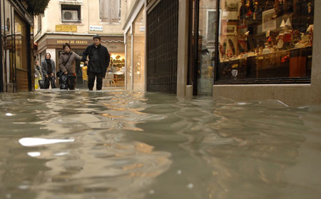 Tourists wade through flood waters in Venice December 1, 2008. Large parts of Venice were flooded on Monday as heavy rains and strong winds lashed the lagoon city, with sea levels at their highest level in 22 years. [China Daily via Agencies] 