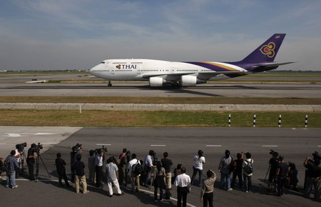 Journalists and airport officials watch the first Thai Airways flight with passengers, arriving from Phuket, land at Bangkok's Suvarnabhumi Airport December 3, 2008, after a week long anti-government protest paralyzed air travel. 