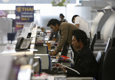 Airport workers start up computers at the check-in counter as anti-government protesters pack up to leave Bangkok's Suvarnabhumi International Airport December 3, 2008. Thailand's main international airport should be back to normal in two days, its general manager said on Wednesday as anti-government protesters packed up and left at the end of an eight-day blockade. [China Daily via Agencies]