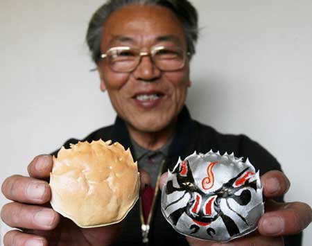 Zhang Shoupei displays crab shells to make a comparation between its natural status and one patterned with traditional local opera facial make-up at Shantang Community in Suzhou, east China's Jiangsu Province, Dec. 3, 2008. Zhang enjoys painting opera facial make-up patterns on crab shells as a hobby.[Xinhua]