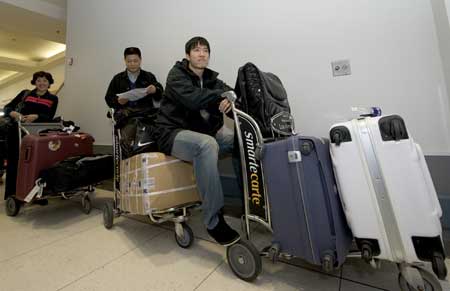 China's star hurdler Liu Xiang (1st R), his mother Ji Fenhua (1st L) and Chinese athletics team head coach Feng Shuyong wait to transfer to Houston at Los Angeles Internaional Airport in the United States on Dec. 3, 2008. [Xinhua]