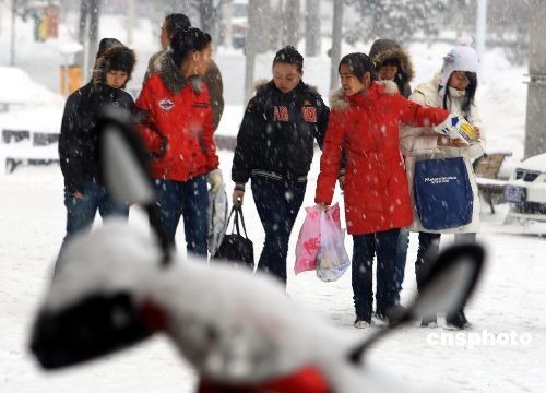 Young people go shopping through the snow in Urumchi, capital of northwestern China's Xinjiang Uygur Autonomous Region, on December 3, 2008. 