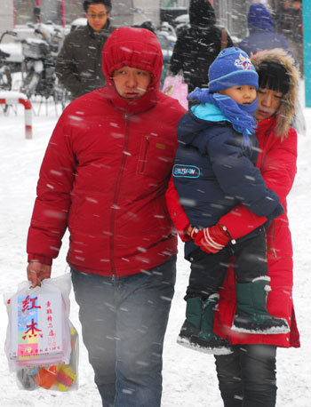 A family makes their way in the snow in Qiqihar of Northeast China's Heilongjiang Province, December 3, 2008. Cold air hit most of the northern part of the country from Wednesday with a dramatic drop in temperatures. [Xinhua]