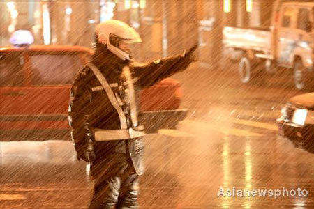 A policeman directs traffic in the snow in Shenyang, capital city of Northeast China's Liaoning Province December 3, 2008. Cold air hit most of the northern part of the country from Wednesday with a dramatic drop in temperatures. [Asianewsphoto]