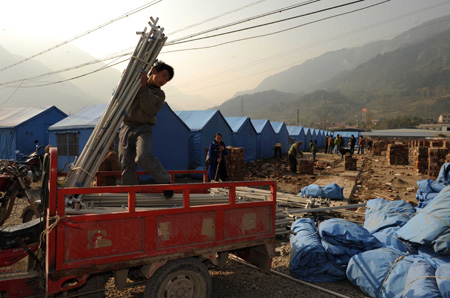 Workers remove temporary tents in Leigu township, Beichuan country, Sichuan province, on Sunday. The county was devastated in the May 12 earthquake. [Xinhua] 