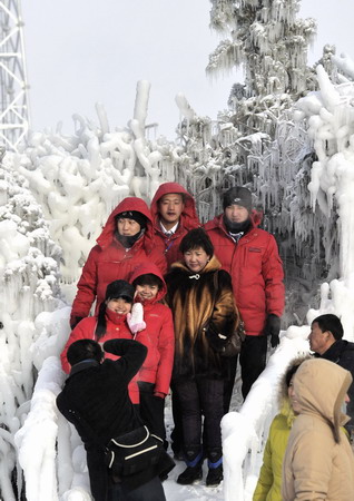 People pose for a picture among snow-covered trees in Aershan, North China's Inner Mongolia Autonomous Region, December 4, 2008. Vast areas from north to central China are experiencing a rare strong cold wave front in recent years, which have forced 26 provinces and municipalities to issue cold weather alerts.[Xinhua]