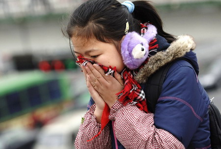 A girl uses her scarf against the cold air in Hefei, East China's Anhui Province, December 4, 2008. Vast areas from north to central China are experiencing a rare strong cold wave front in recent years, which have forced 26 provinces and municipalities to issue cold weather alerts.[Xinhua] 