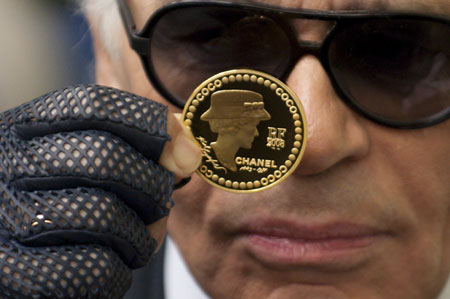 German fashion designer Karl Lagerfeld presents a 5 Euro coin, designed by him, to commemorate the 125th anniversary of French fashion designer Gabrielle 'Coco' Chanel's birth at the Hotel de la Monnaie, the national mint responsible for making official coins and medals, in Paris Nov. 19, 2008. [China Daily/Agencies]