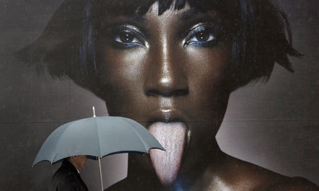 A man with an umbrella walks past an advertisement in Berlin Apr. 15, 2008.[China Daily/Agencies]