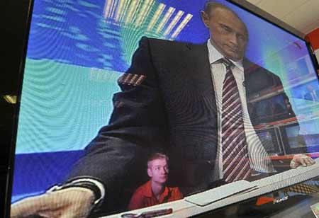 A shop keeper is reflected in a television screen at an electronics shop in Veliky Novgorod during Russian Prime Minister Vladimir Putin's annual question-and-answer session with the Russian people, December 4, 2008. 