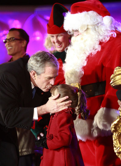 U.S. President George W. Bush kisses four-year-old singer Kaitlyn Maher alongside a person dressed as Santa Claus after she performed at the National Christmas Tree lighting ceremony in Washington December 4, 2008. 