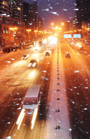 Vehicles travel on the street as heavy snow falls in Harbin, Northeast China&apos;s Heilongjiang Province, December 4, 2008. Vast areas from north to central China are experiencing a rare strong cold wave front in recent years, which have forced 26 provinces and municipalities to issue cold weather alerts.[Xinhua]