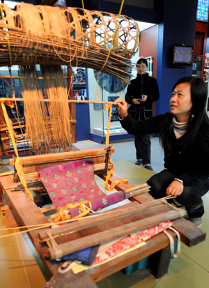 Visitors look at a loom displayed in the Museum of Nationalities in Nanning, capital of southwest China's Guangxi Zhuang Autonomous Region, on Dec. 5, 2008. 